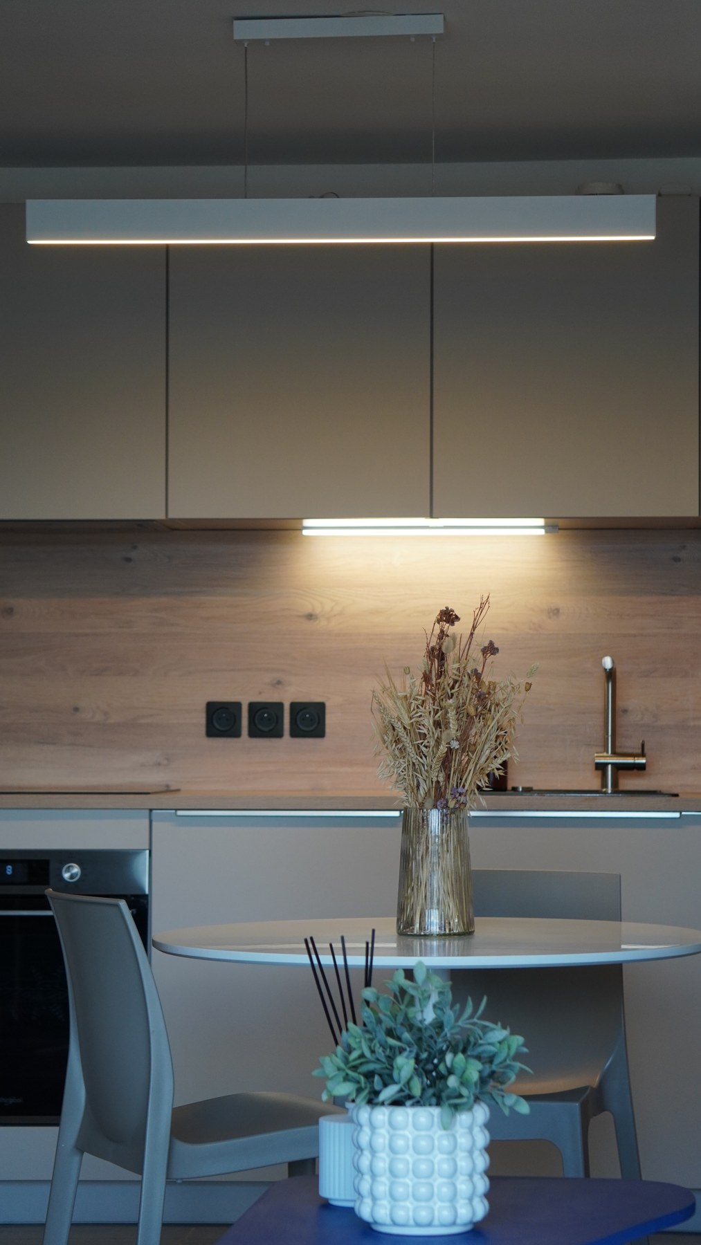 Appartement bordelais réalisé : cuisine aux façades claires, crédence en bois et espace repas avec table ronde
